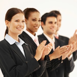 Close-up of four business executives standing in a line and applauding